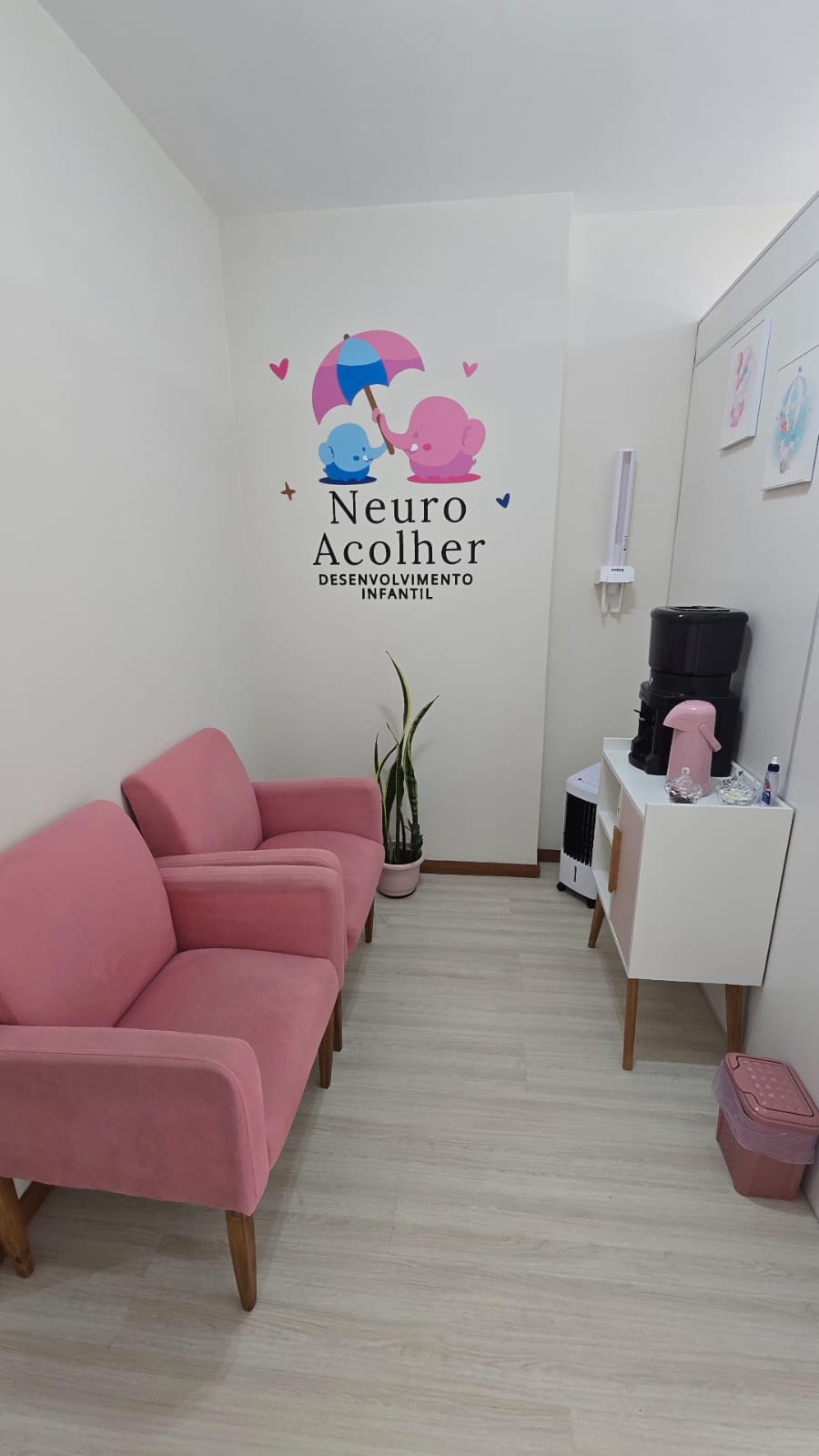 Recepção do Neuro Acolher com poltronas rosas e logo na parede