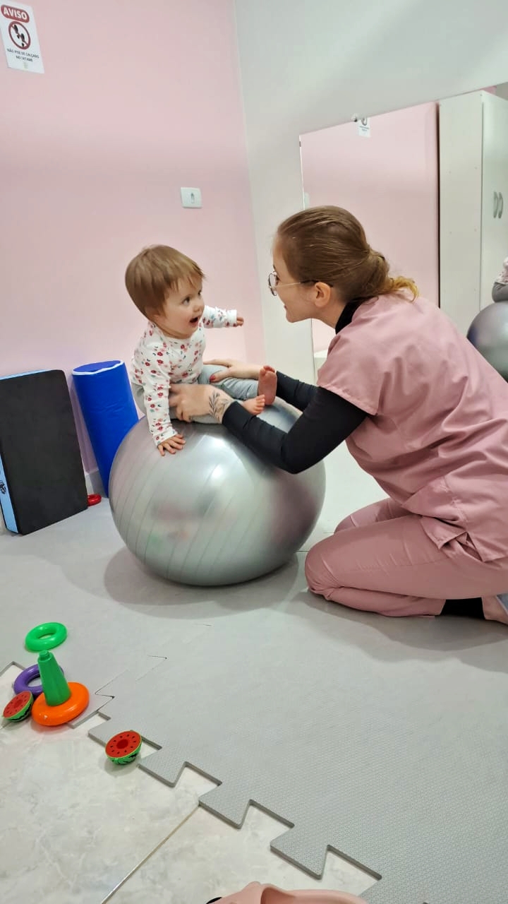 Fisioterapeuta estimulando bebê sobre bola terapêutica no Neuro Acolher