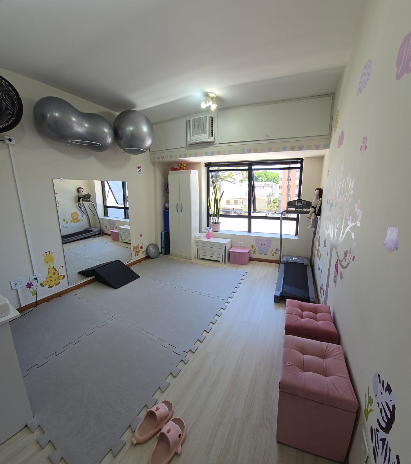 Sala de fisioterapia pediátrica com bolas terapêuticas e decoração infantil